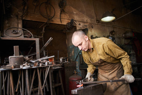 Blacksmith in the production process of metal products handmade in the workshop - Foto, Bild