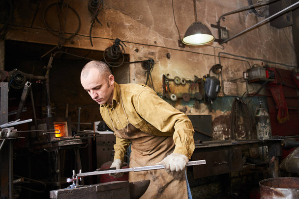 Blacksmith in the production process of metal products handmade in the workshop - Photo, Image