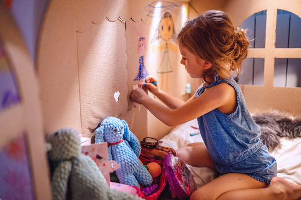 Charming girl playing in toy house - Foto, afbeelding