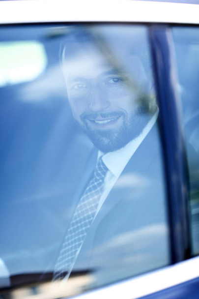 Because of a glass of smiling businessman in the back seat of a car. - Фото, изображение