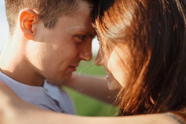 jeune, heureux, couple aimant debout dans un champ vert, contre le ciel, dans les bras, et en se regardant
, - Photo, image