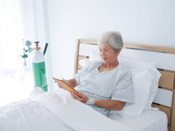 Elderly woman using laptop in hospital room. - Fotoğraf, Görsel