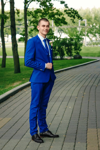 Чоловік, наречений в класичному синьому костюмі на тлі зеленої природи. Весілля, наречений, створення сім'ї
. - Фото, зображення