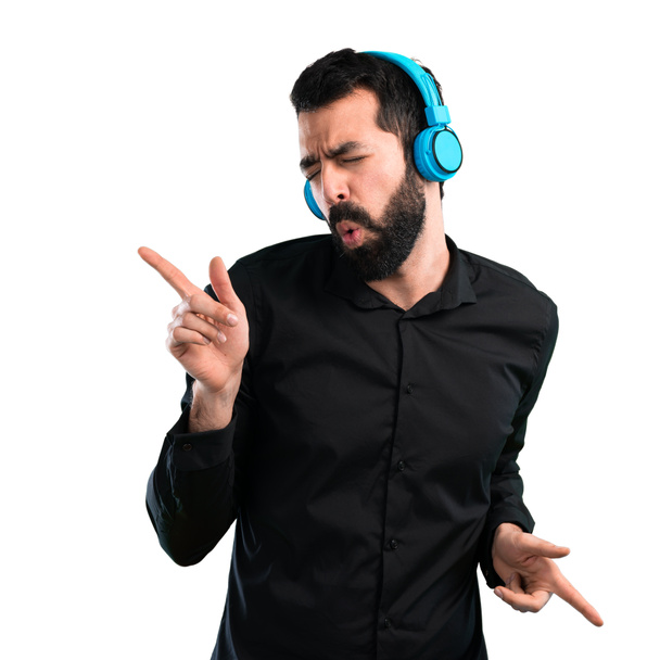 Handsome man with beard listening music on white background - Фото, изображение