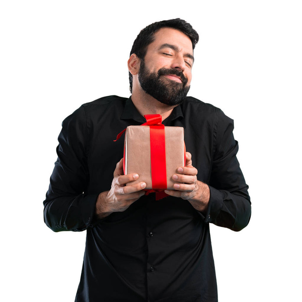 Hombre guapo con barba sosteniendo un regalo sobre fondo blanco
 - Foto, imagen