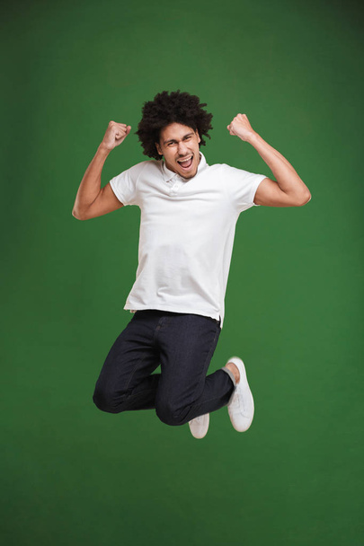 Photo of happy young african curly man isolated over green wall background make winner gesture. - Foto, imagen