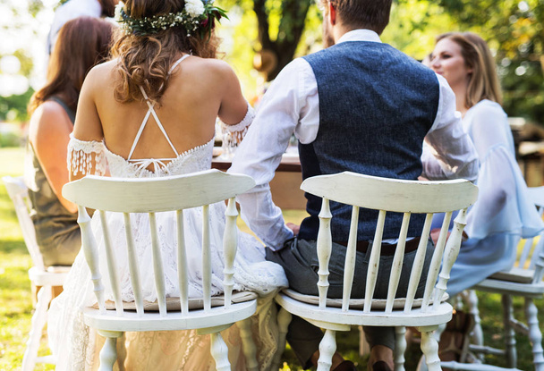 Mariée et marié avec invités à la réception de mariage à l'extérieur dans la cour arrière
. - Photo, image
