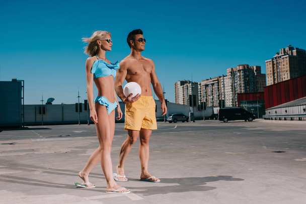 jeune couple en vêtements de plage avec ballon de volley sur le parking
 - Photo, image