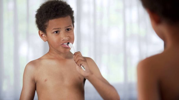 Male child brushing teeth diligently bathroom, tooth plaque prevention, health - Foto, immagini
