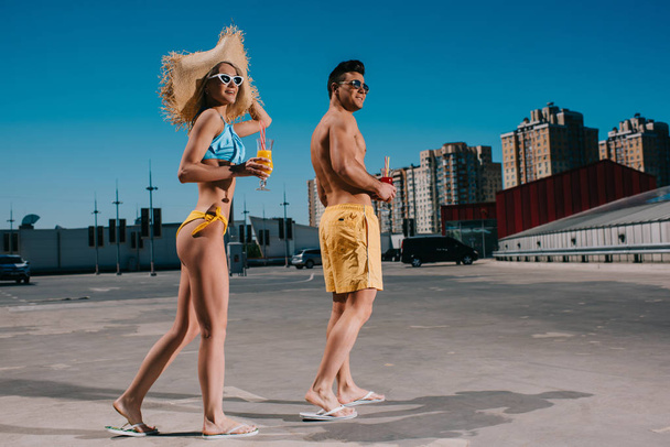 young happy couple in swimsuits with refreshing cocktails standing on parking - Foto, Imagem