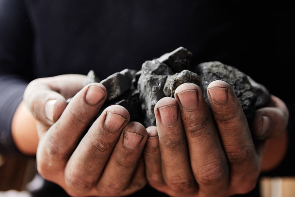 Ανθρακωρύχος στα χέρια άνθρωπος του παρασκηνίου άνθρακα. Άνθρακα εξόρυξη ή ενεργειακή πηγή, προστασία του περιβάλλοντος. Βιομηχανικούς άνθρακες. Ηφαιστειακό πέτρωμα. - Φωτογραφία, εικόνα