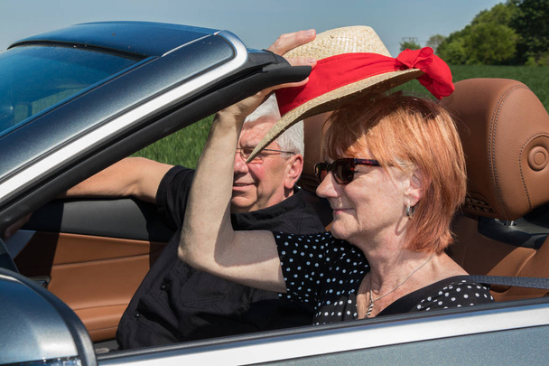 older couple drives with a luxury convertible car on a sunny day - Photo, Image