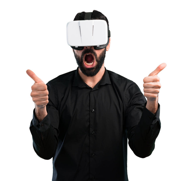 Hombre guapo con barba usando gafas VR sobre fondo blanco
 - Foto, imagen
