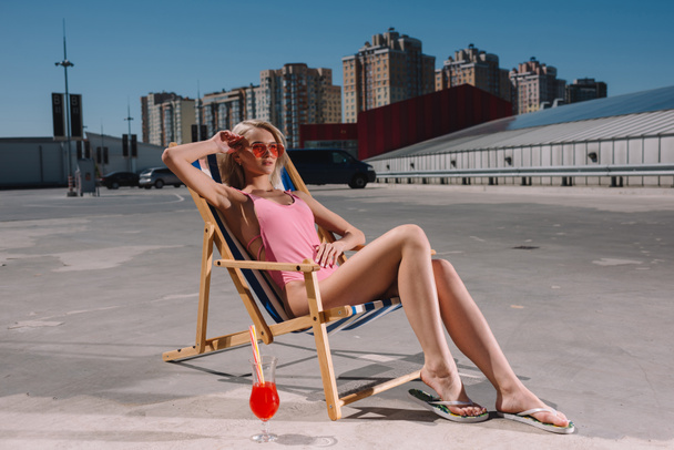 attractive young woman relaxing in sun lounger on parking - Foto, imagen