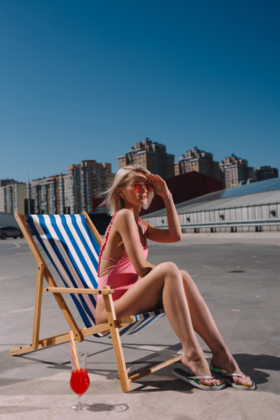 stylish young woman relaxing in sun lounger on parking - Photo, Image