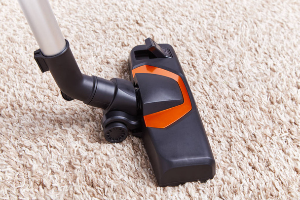 Couper morceau d'aspirateur dans le travail sur le dessus de la surface de tapis texturé doux à la maison
. - Photo, image