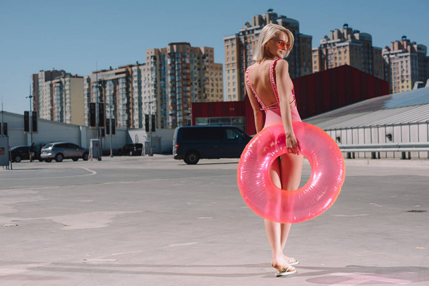 belle jeune femme en maillot de bain avec anneau gonflable sur le parking
 - Photo, image