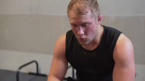 Muž unavený fitness odpočívá po cvičení a utíral si pot z obličeje v tělocvičně - Záběry, video
