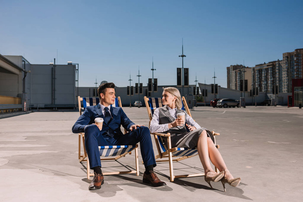 young business people relaxing on sunbeds with coffee to go on parking - Foto, Imagem