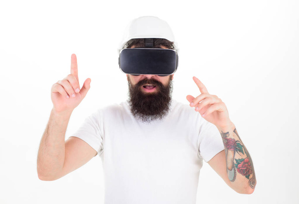Man with beard in VR glasses and helmet, white background. Hipster on concentrated face use modern technology. Virtual reality concept. Guy with head mounted display interact in virtual reality - Fotoğraf, Görsel