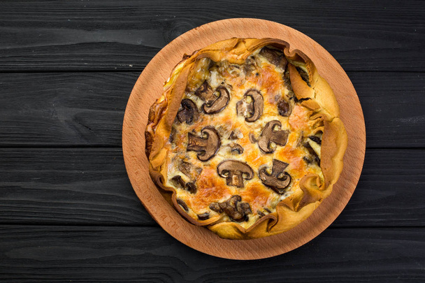 Pie with champignons and cheese on a wooden plate - Foto, Bild