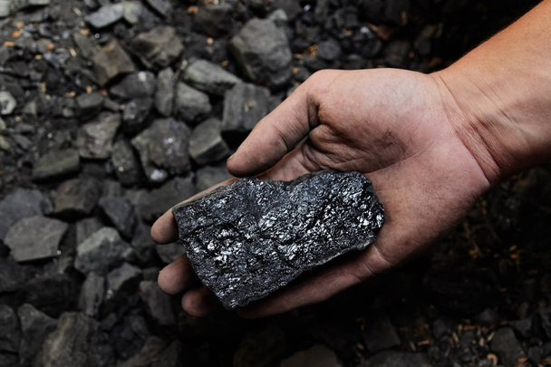 Вугільний шахтар у руках людини вугільного фону. Видобуток вугілля або джерело енергії, захист навколишнього середовища. Промислове вугілля. Вулканічний камінь
. - Фото, зображення