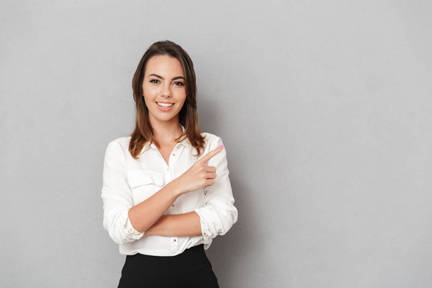 Image of happy young business woman standing isolated over grey wall background looking camera pointing. - Zdjęcie, obraz