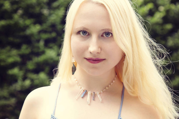 Retrato de una hermosa mujer joven con cabello rubio, ojos azules y collar de cuarzo cristal
 - Foto, Imagen