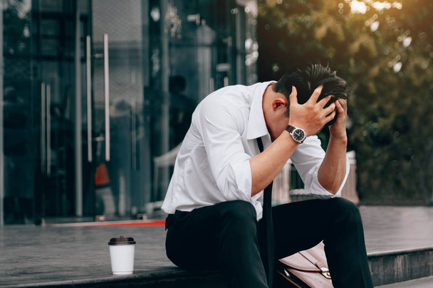 Aasialainen nuori liikemies stressi istuu edessä toimistossa kädet peittävät päänsä vastaan
. - Valokuva, kuva