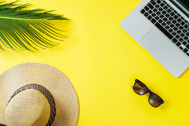 Working space: Laptop, palm leaf, clipboard hat on a yellow background. Top view, flat lay, space for text - Photo, Image
