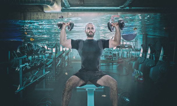 funny image of man training with dumbbell in a flooaded gym - Foto, Imagem