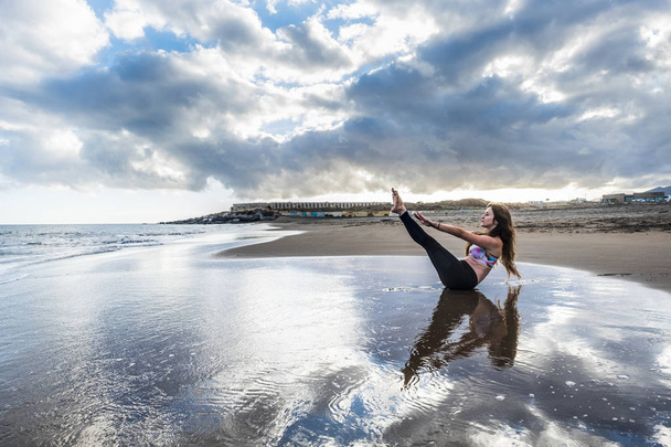 Pilates fitness gondoskodik a test többi és a pozíció a fiatal kaukázusi nő a parton: beach szálláshelyén. festői kép test egészségügyi koncepció. jóga, kiegyensúlyozott kapcsolatot, és az érzés, a természettel. meditáció-szabadidő. - Fotó, kép