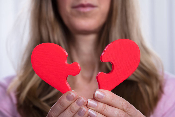 Mujer mostrando corazón roto rojo en sus manos
 - Foto, imagen