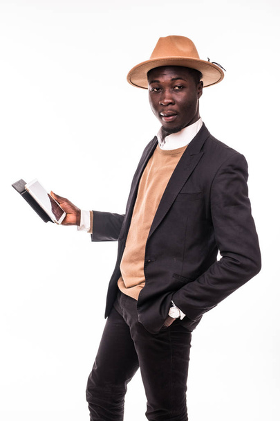 Smiling african american businessman using tablet wearing in suit and hat . Young man in suit working with portable computer, isolated on white background. Business and modern technologies concept - Photo, Image