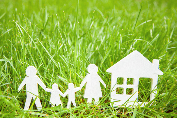 Familie uit vader, moeder, zoon en dochter in de buurt van het huis op groene gras. Concept is ecologisch schoon huis voor de familie. Ruimte voor tekst kopiëren - Foto, afbeelding