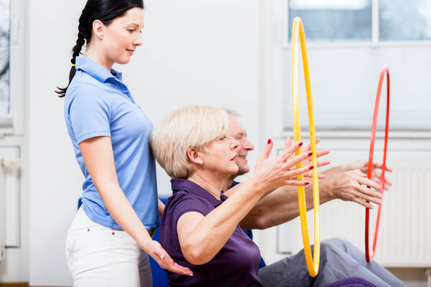 Старшая пара в физиотерапии делает упражнения с обручем хула
 - Фото, изображение