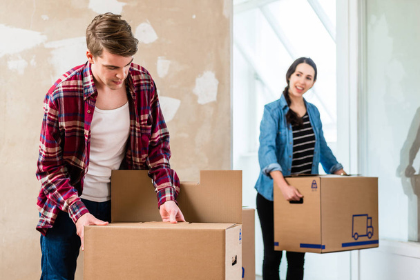 Young man opening a box while moving in with his girlfriend - Photo, Image