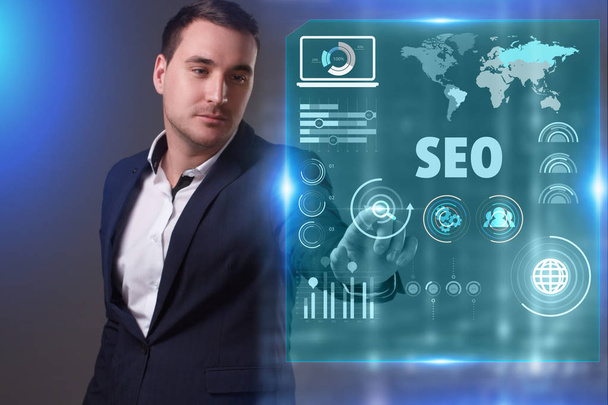Business, Technology, Internet and network concept. Young businessman working on a virtual screen of the future and sees the inscription: SEO - Foto, afbeelding