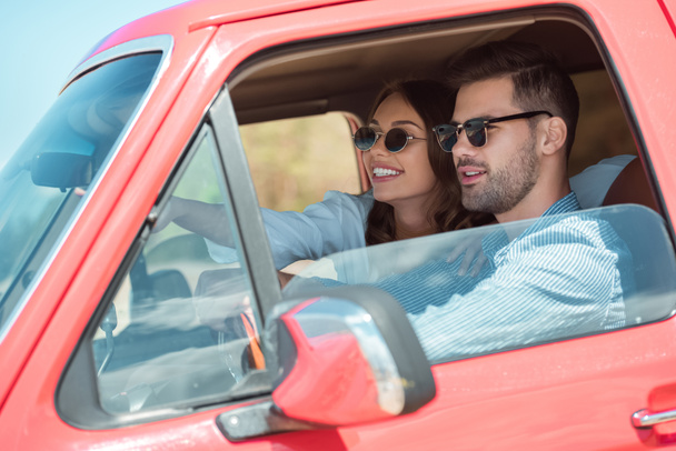 赤い車を運転して美しい幸せなカップル - 写真・画像