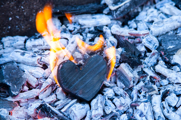 Heart burns in the fire. Wooden heart was charred and the flames on the coals. The concept of strong love, burning passion, broken relationships - Photo, Image