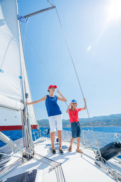 Boy with his sister on board of sailing yacht on summer cruise. Travel adventure, yachting with child on family vacation. - Foto, Imagem
