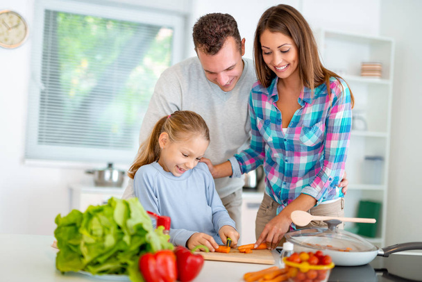 young family cooking healthy meal in domestic kitchen - Photo, Image
