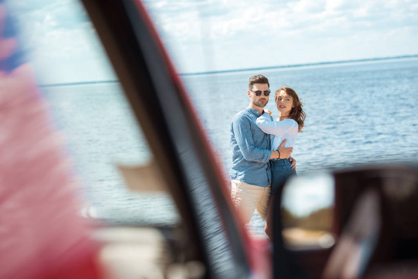 selective focus of car and young couple hugging near the sea - Foto, imagen