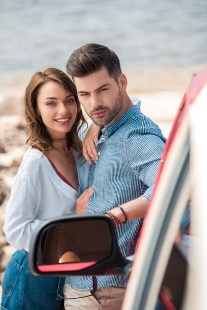 smiling young couple hugging near car on vacation - Foto, imagen