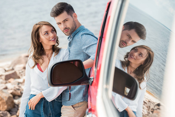 young couple of travelers hugging at car near the sea - Foto, imagen