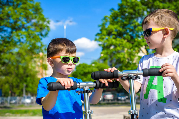 Deux petits garçons montés sur des scooters. Avertissez l'été ou le printemps. Frères garçon enfant s'amuser ensemble portant des lunettes de soleil. Concept d'amitié
. - Photo, image