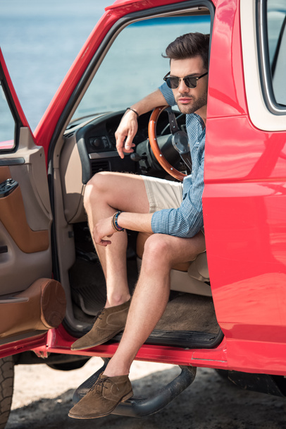 赤い車に座っているサングラスでハンサムな男 - 写真・画像