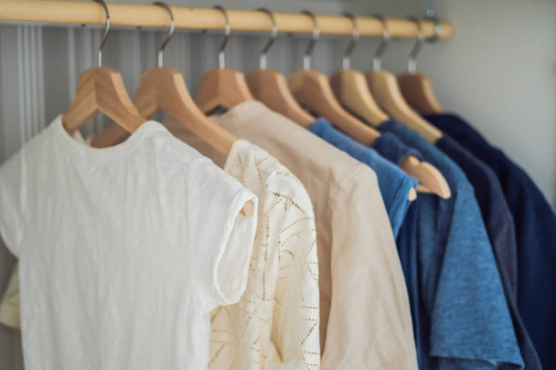 Clothes on hangers in the cabinet gradient from white to dark blue. - Фото, зображення
