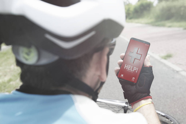 Τραυματίες ποδηλάτης εκμετάλλευση του smartphone καλώντας την ομάδα διάσωσης με την απλή φιλική προς το χρήστη έξυπνο τηλέφωνο εφαρμογή  - Φωτογραφία, εικόνα