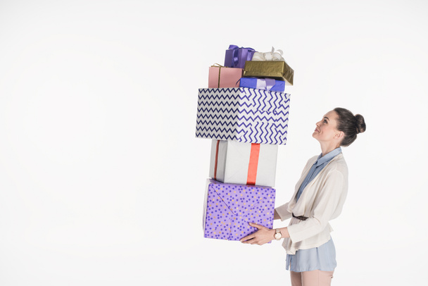 side view of woman holding pile of wrapped presents isolated on white - Фото, зображення